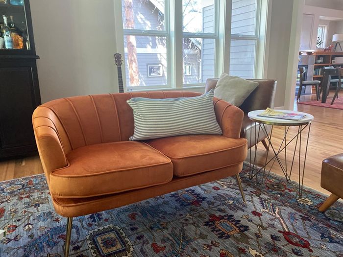A reviewer's photo of an orange loveseat placed in a family room.