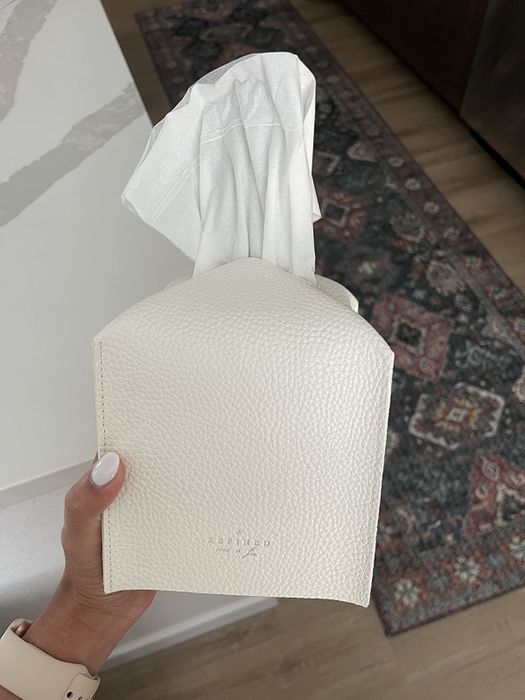 A reviewer holding a white faux leather tissue box cover in their hands