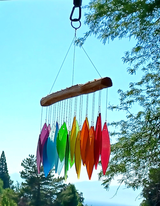 A colorful set of wind chimes swaying outdoors, with a breathtaking natural backdrop.