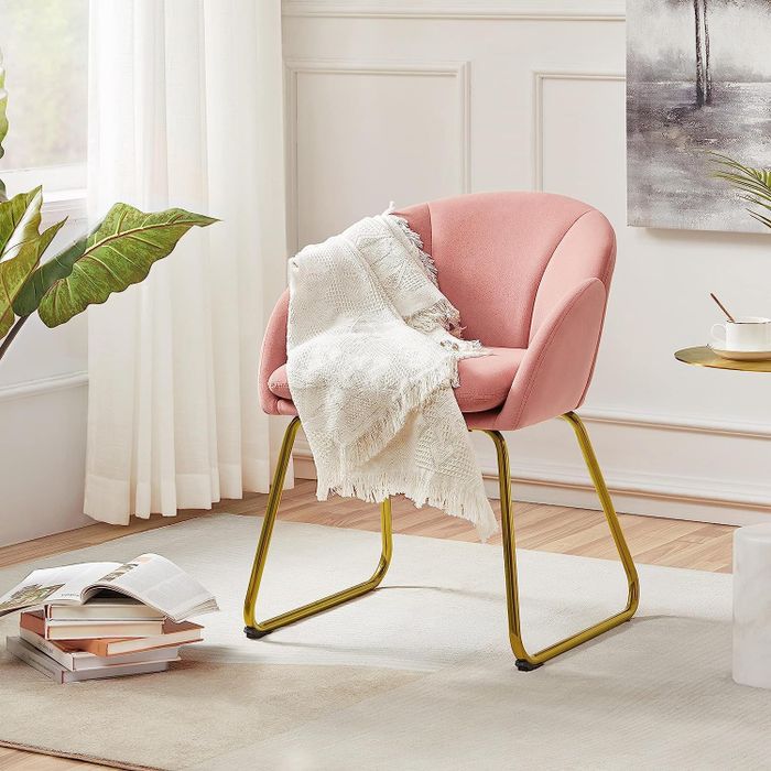 A modern pink accent chair with stylish gold legs.