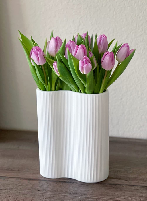 A white infinity-shaped vase holding a reviewer’s tulips.