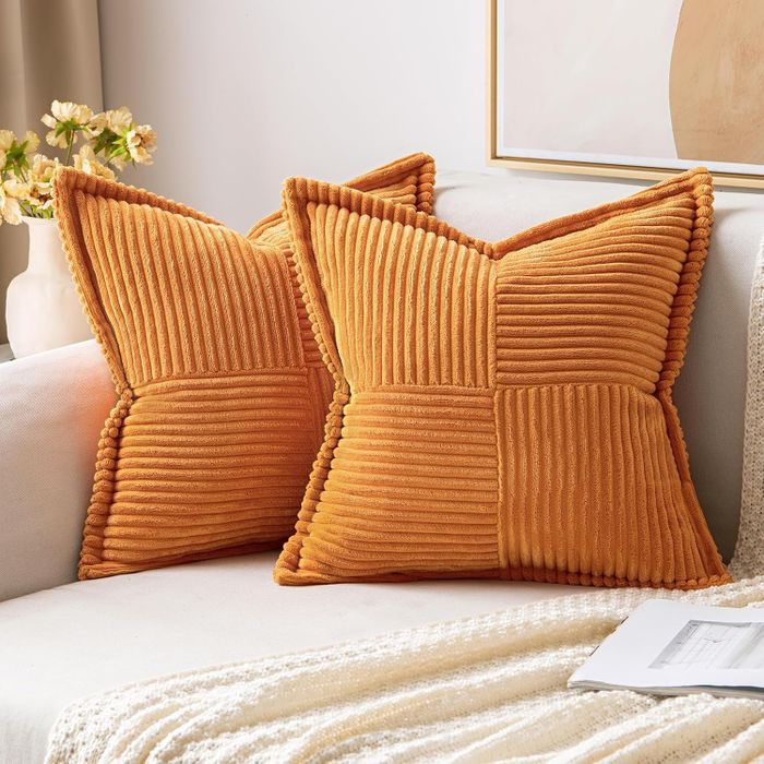 Two textured decorative pillows rest on a couch, with a magazine and a blanket placed beside them.