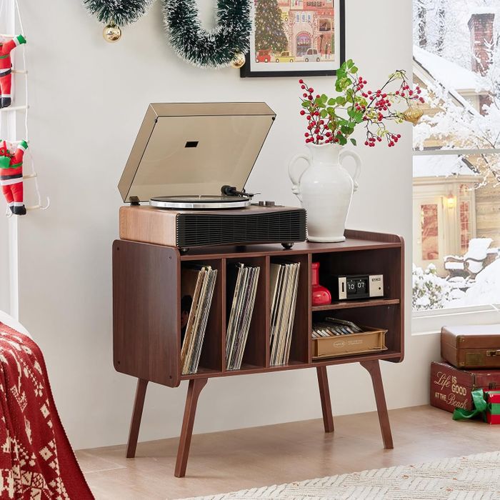 Mid-century modern record player and vinyl storage unit placed in a cozy, festive room with holiday decorations and a snow-covered window outside