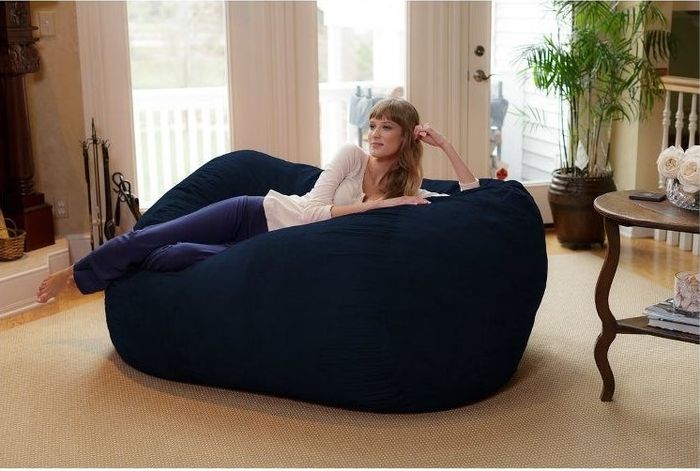 A person lounging on a navy blue bean bag placed in a cozy living room