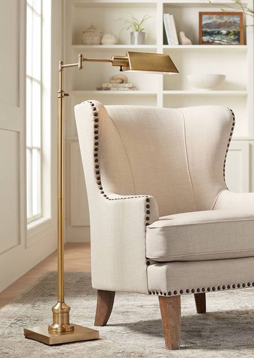 The gold floor lamp positioned next to a cream armchair, casting a warm glow across the space.