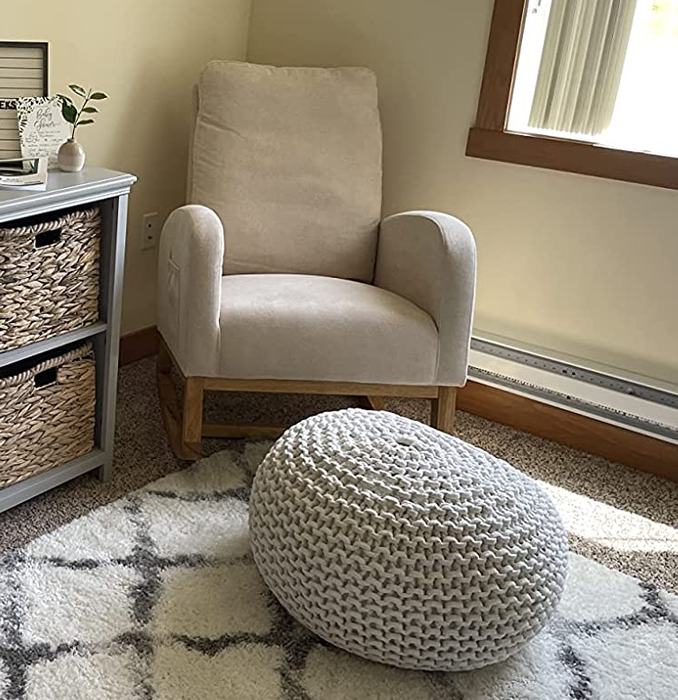 A reviewer's photo of a white rocking chair placed in a nursery.