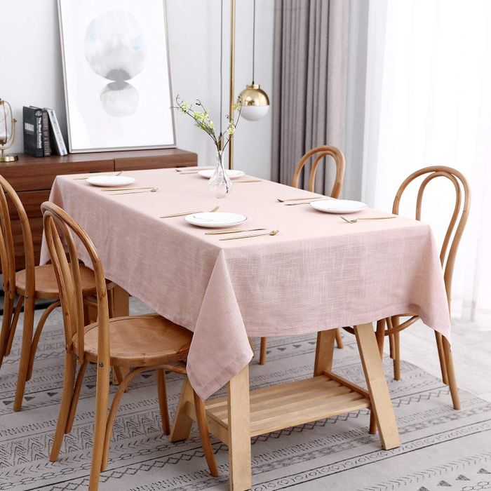 A soft pink faux linen tablecloth elegantly draped over a cozy four-seater dining table