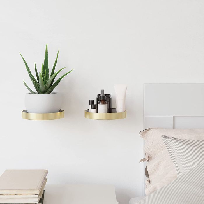 two brass shelves displaying a succulent and skincare products