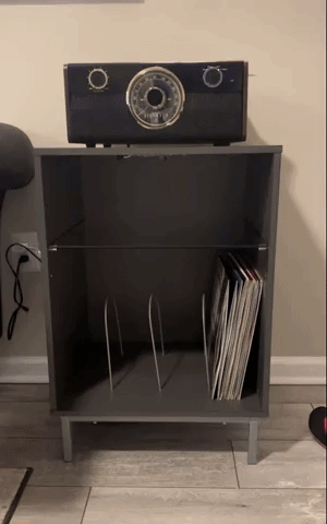 Reviewer video showcasing a wooden record player stand with a glass shelf and vinyl separator, featuring color-changing LED lights