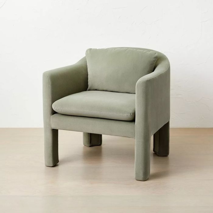 Modern armchair with a curved backrest and a plush, cushioned seat, upholstered in soft fabric, showcased in a shopping guide.