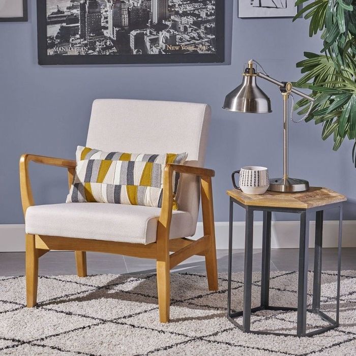 An ivory wooden club chair placed in a living room beside a chic coffee table