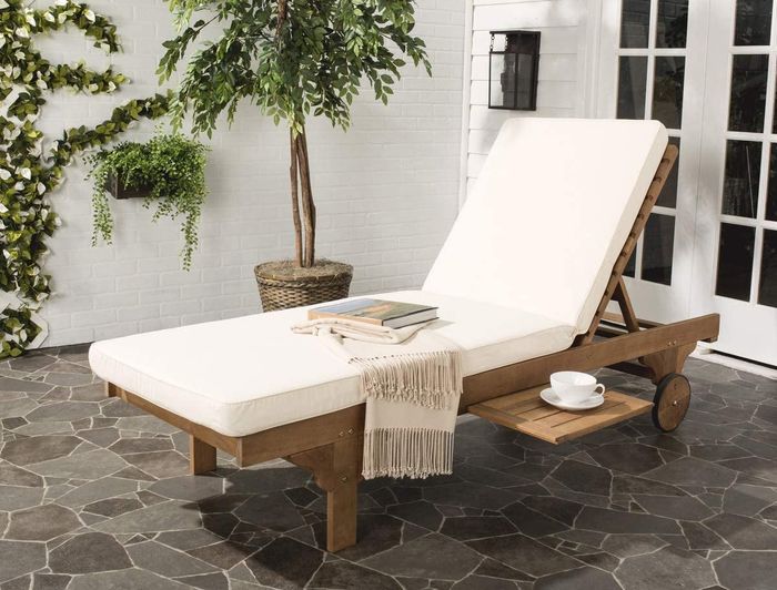 The white lounge chair adorned with books and a cozy blanket.