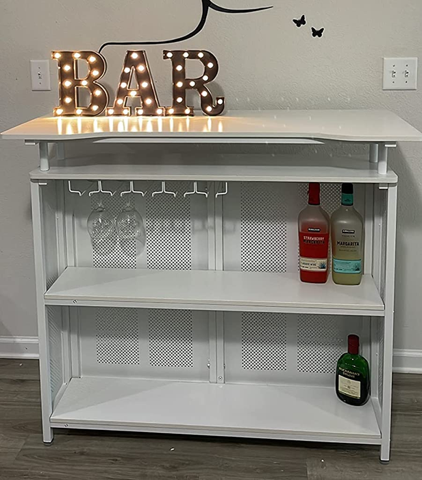 Reviewer image of a white metal bar cabinet with bottles and glasses arranged on the shelves