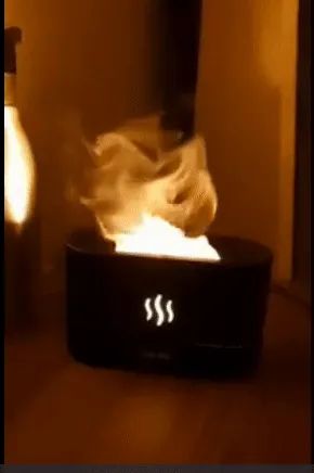 A black humidifier with light effects that mimic flames coming out of it