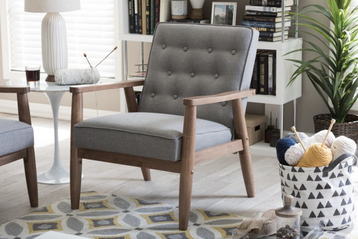 A gray faux leather wooden lounge chair elegantly placed in a cozy living room setting.
