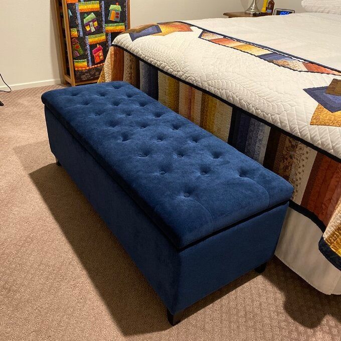 reviewer photo showcasing a navy blue ottoman at the foot of the bed