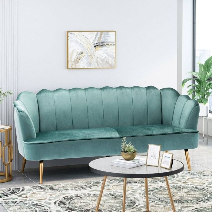 A turquoise and gold three-seater velvet channel shell sofa placed in a chic living room.