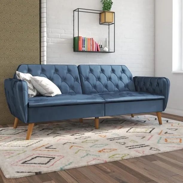 A blue velvet couch resting on a geometric rug.