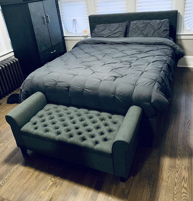 a reviewer’s photo of the bench placed at the foot of the bed