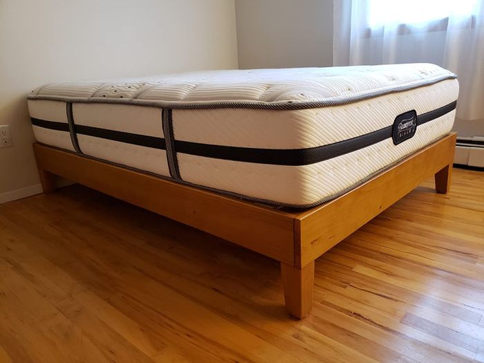 a reviewer’s image of the rustic pine full-size platform bed with a mattress placed on top