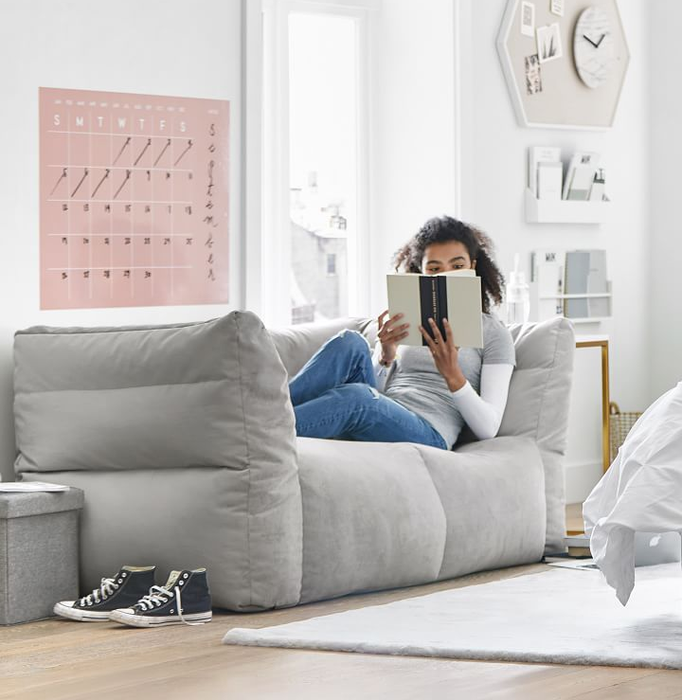 A model relaxing with a book on the cozy gray velvet sofa.
