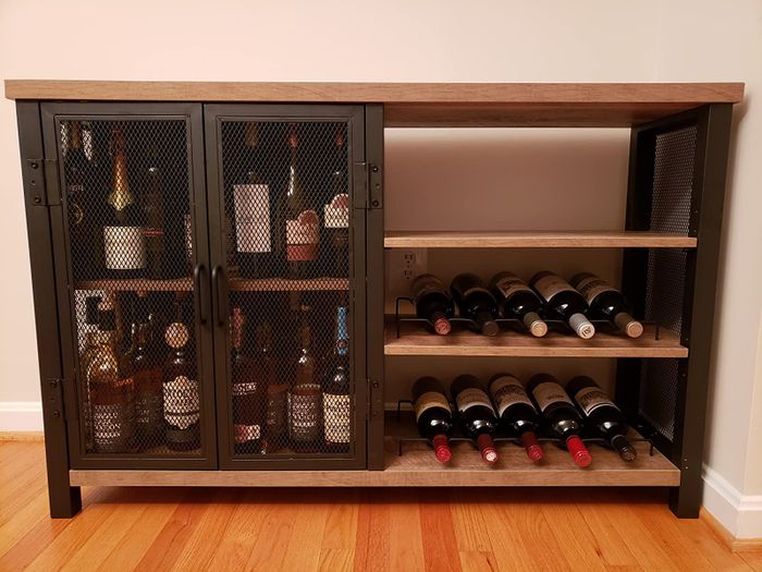 Reviewer image of a light wood and black metal bar cabinet with closed doors and open shelving spaces