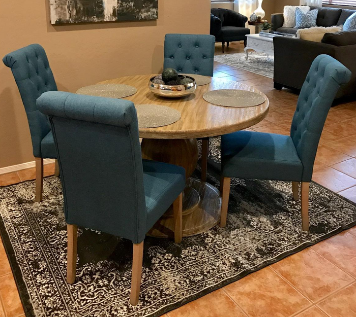 Reviewer image of four blue tufted chairs arranged around a round dining table