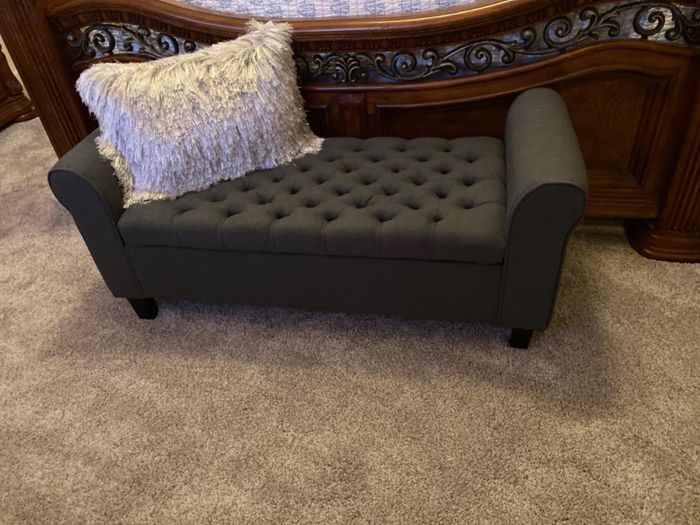 a reviewer’s photo of the black bench at the foot of the bed