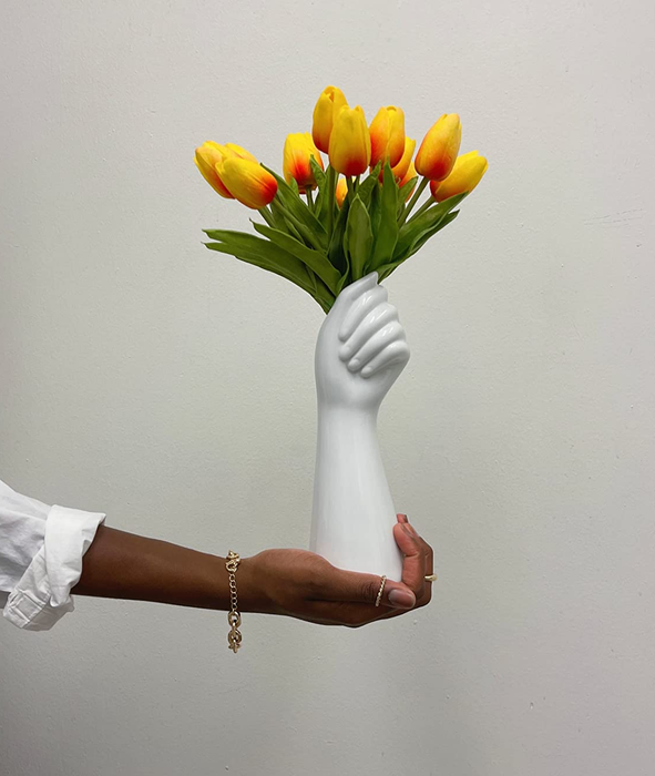 Reviewer photo of yellow tulips inside a white hand-shaped vase placed on a table with a white tablecloth
