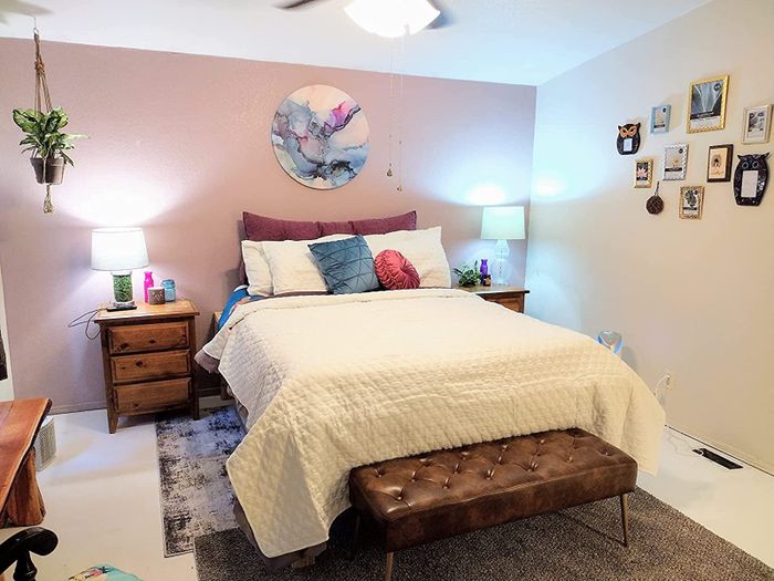 reviewer photo of the bench in brown faux leather at the foot of the bed