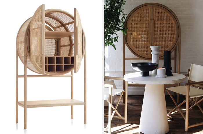 Sleek circular bar cabinet with open doors revealing shelves, positioned elegantly behind a dining table and chairs