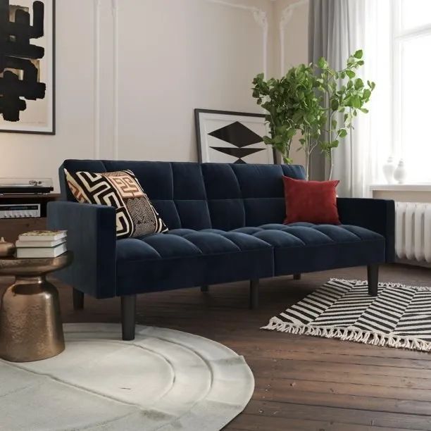 Blue velvet sofa placed on a dark wood floor