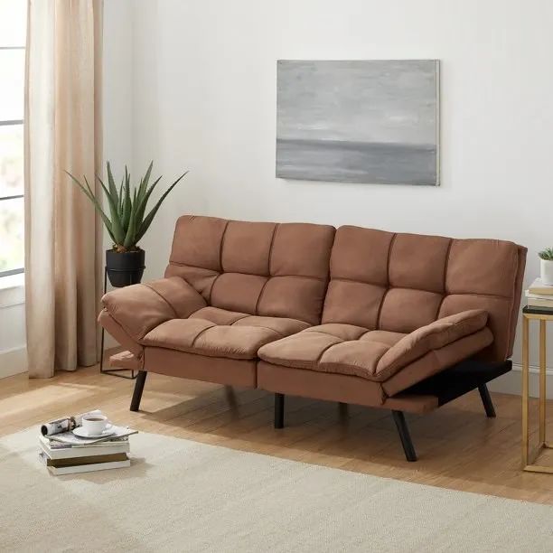 Beige futon on a wooden floor with books placed in front of it.