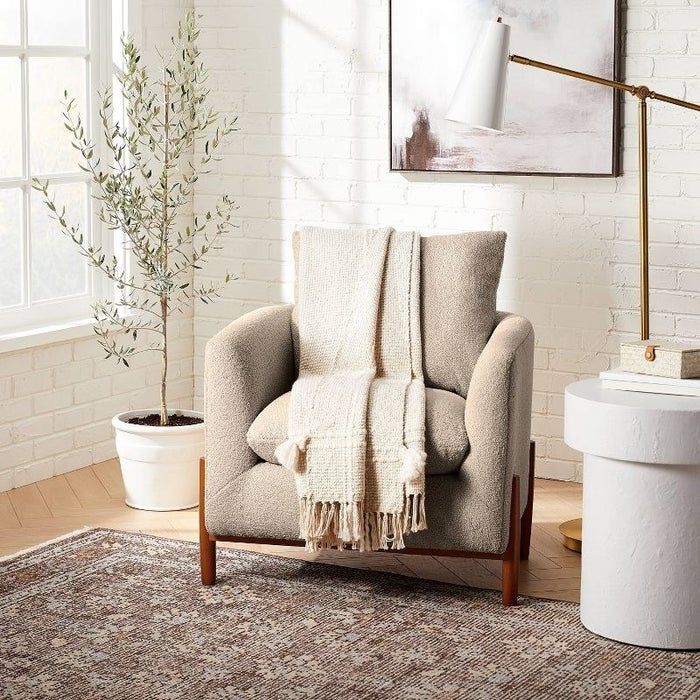 A picture of an accent chair featuring a full Sherpa finish and wooden legs.