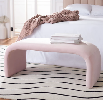 pink curved bench positioned at the foot of the bed