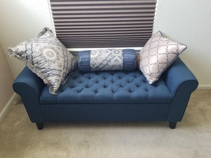 a photo from a reviewer showing the ottoman with a few decorative throw pillows placed on top