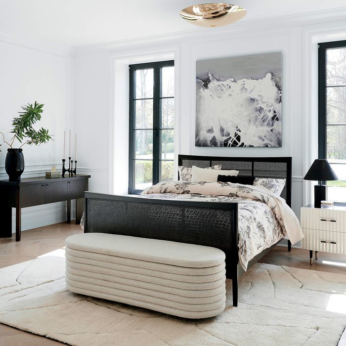 a pleated white storage bench at the foot of a bed