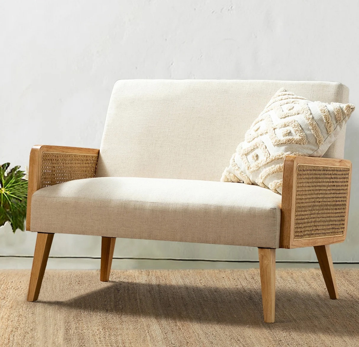 A white rattan loveseat, offering a stylish and cozy seating option for any room.