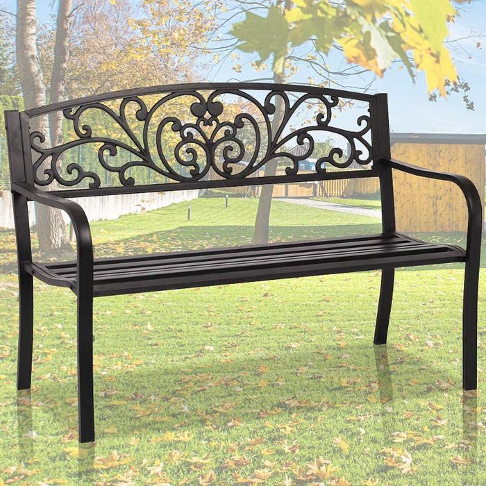 A black wrought iron bench placed on grass outside
