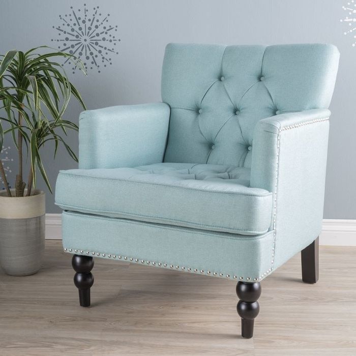 An image of a blue tufted armchair with solid birch legs.