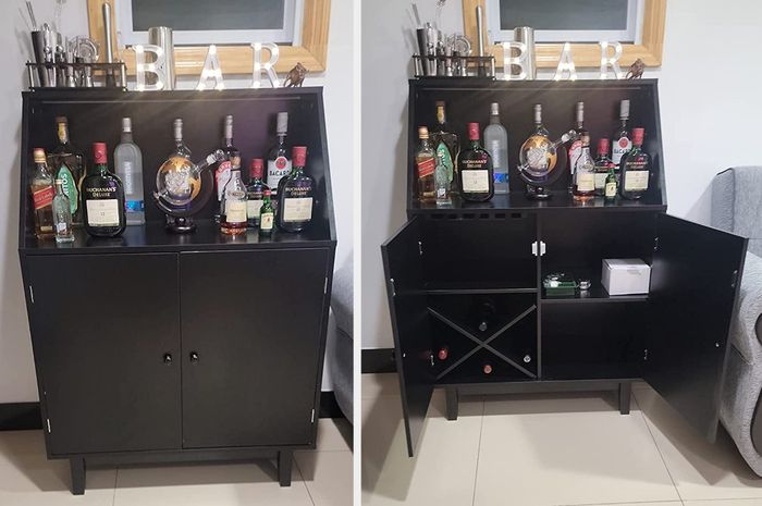 Reviewer image of a small black bar cabinet with cubbies and bottles neatly arranged