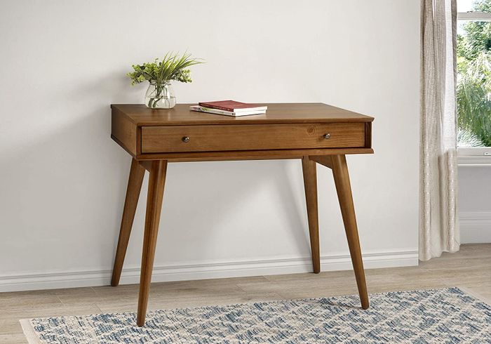 the writing desk adorned with a vase and two books resting on its surface