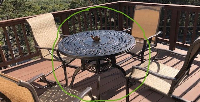 A review image of a black wrought iron patio table with rounded legs and four surrounding chairs