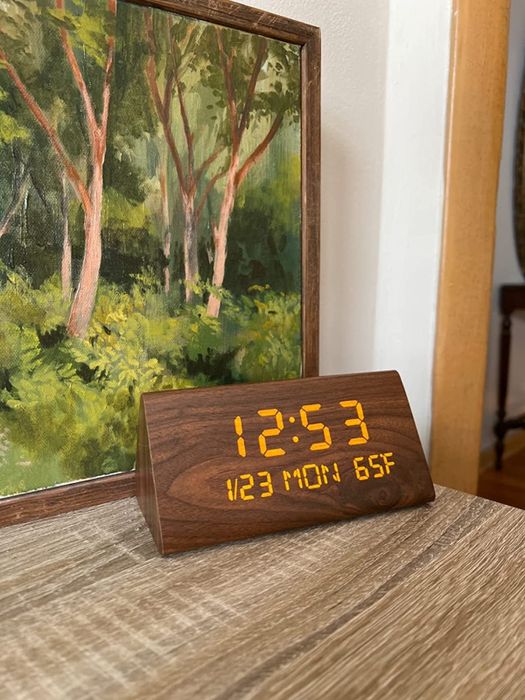 A reviewer shares a close-up of their wooden clock on a side table