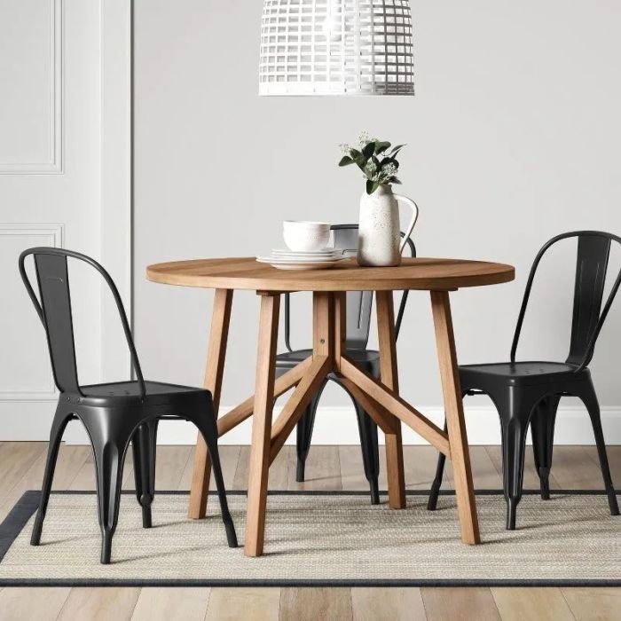 The table with three black chairs and plates arranged on top