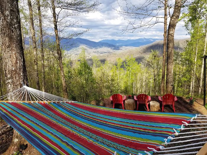 Reviewer photo of the striped hammock hanging between two trees, set against a beautiful view of forest and mountains.
