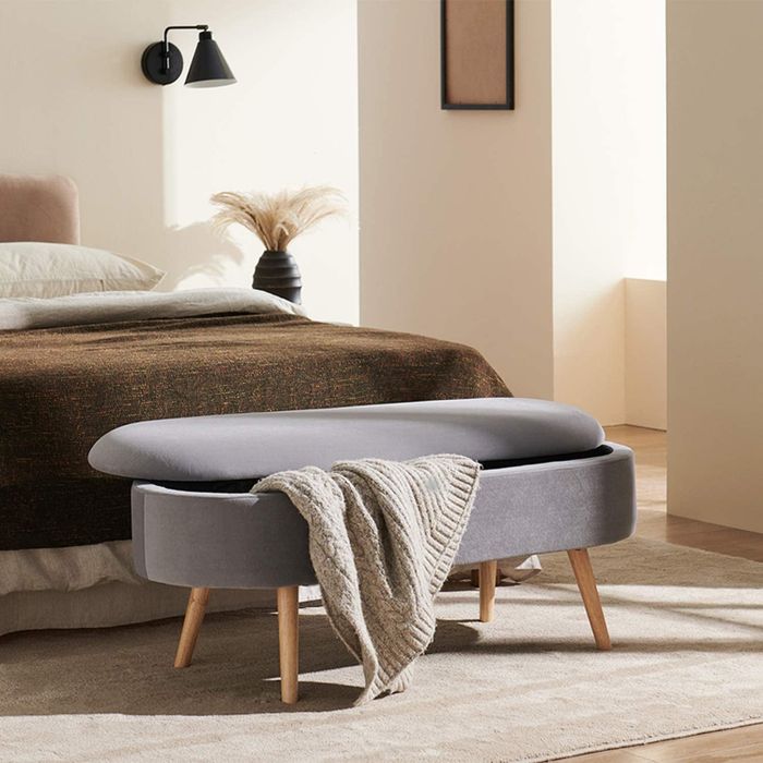 the storage bench positioned at the foot of the bed with a blanket draped over it