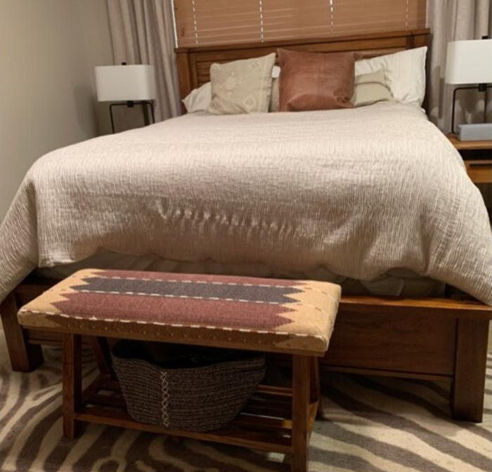 reviewer photo of the wooden bench at the foot of the bed