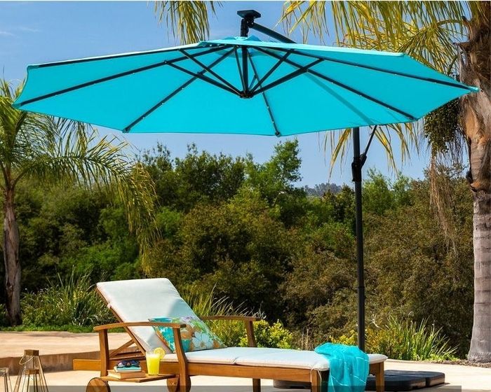 An acacia wood lounge chair in cream shade, sitting pretty under a blue umbrella.