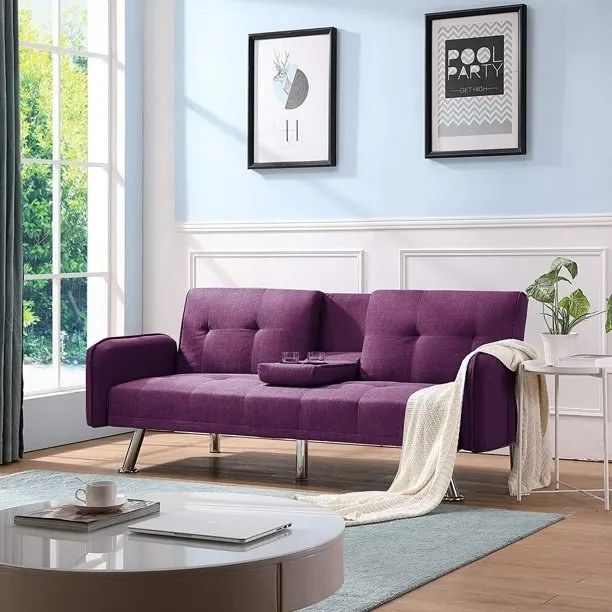 The purple futon featuring two cup holders and a soft white blanket draped over it